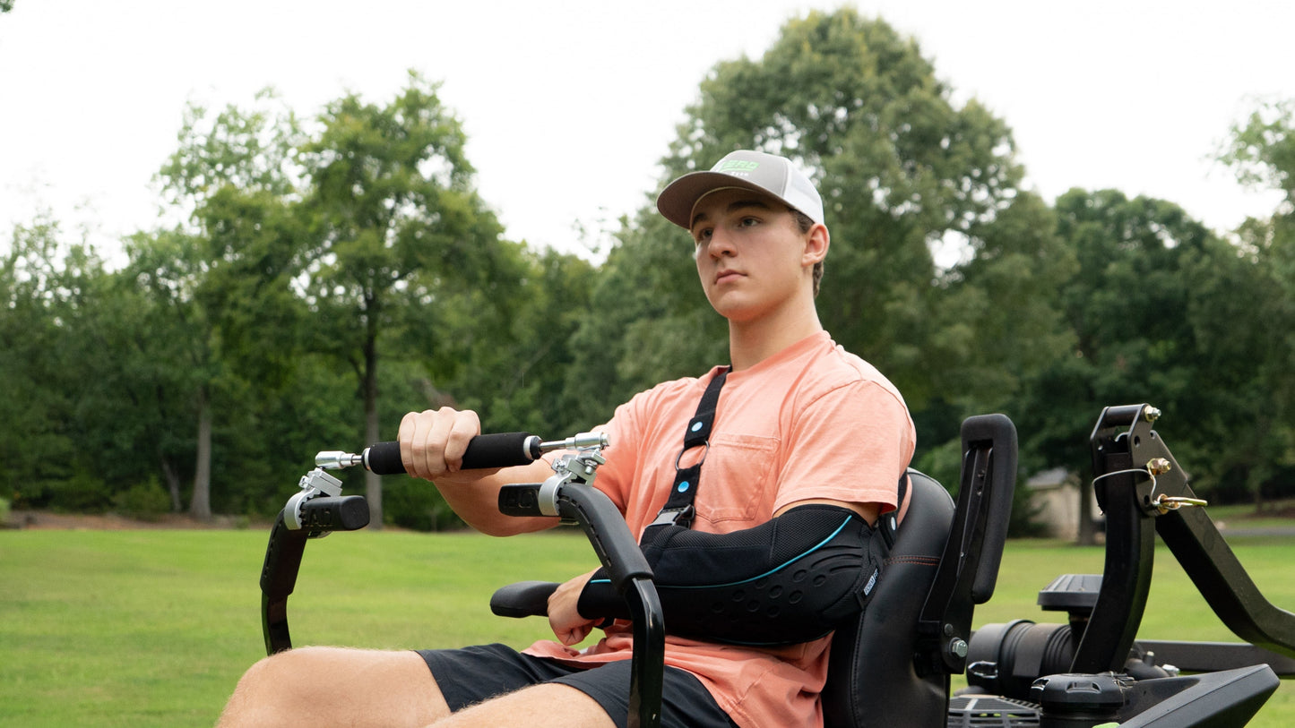 Zero Turn mower being operated with one hand by a landscaper with a shoulder injury as seen by the sling. The Zero-Turn Bar Increases accessibility by allowing full functionality with one hand.